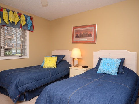 Two cozy twin beds dressed in soft denim-blue linens await your restful nights, while cheerful pops of color add a playful, welcoming touch to your private retreat.