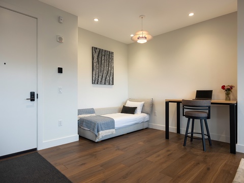 Step into your modern, minimalist retreat. Warm wood floors lead you to a streamlined workspace and cozy daybed—perfect for unwinding after exploring nearby attractions or catching up on your favorite shows.
