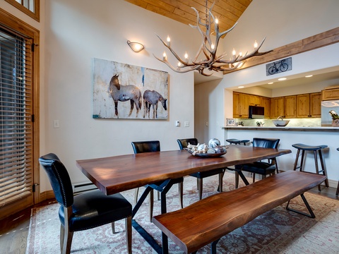 Gather around this handcrafted wooden table beneath a stunning antler chandelier. Your mountain retreat awaits with vaulted ceilings and a fully-equipped kitchen ready for memorable meals together.