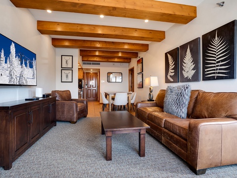 Sink into plush leather seating beneath rustic exposed beams, where mountain-inspired art and warm wood tones create your perfect retreat after a day of adventure.