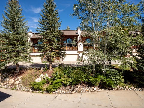 This mountain retreat sits nestled among mature evergreens and aspens, offering a peaceful arrival experience with private garages and well-maintained landscaping.