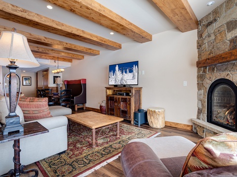 Curl up by the stone fireplace in this spacious living room, where exposed wood beams and mountain charm create your perfect alpine retreat after a day on the slopes.