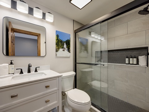 Your private bathroom features a sleek walk-in shower with modern fixtures, a vanity with ample storage, and thoughtful touches like plush towels and premium amenities to start your day refreshed.
