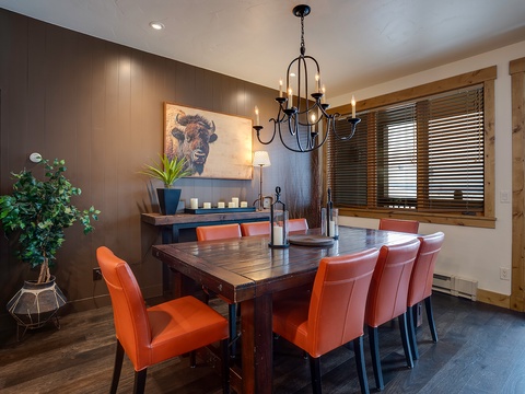 Gather around this handsome dining table with vibrant orange chairs, perfect for enjoying meals together. Warm lighting and rustic mountain-inspired décor set a welcoming tone for your stay.