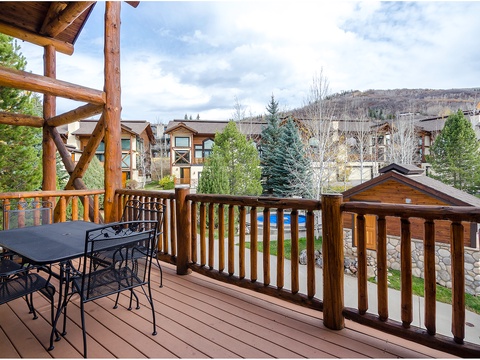 Overlooks a peaceful neighborhood with mountain terrain rising in the background. The property is situated among alpine homes and evergreen trees in a scenic mountain community.