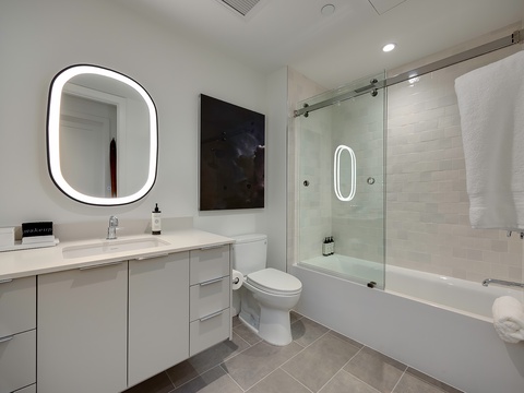 Step into your spa-like retreat with sleek modern design, soaking tub, and glass-enclosed shower. Fresh towels and upscale amenities await your arrival.