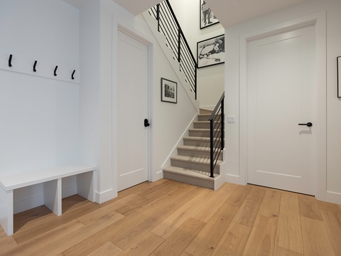 Step inside to a bright and welcoming entryway with warm hardwood floors, crisp white walls, and thoughtful details like hooks for your coats and a cozy bench to drop your bags.