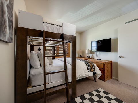 This cozy bedroom features a clever bunk bed arrangement and a welcoming queen bed, offering flexible sleeping spaces for your group or family. Warm wood tones and modern touches create an inviting retreat after your mountain adventures.