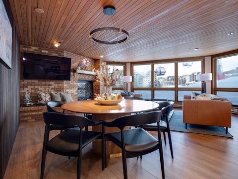 Your inviting living space blends warm wood tones with modern comfort. Gather around the dining table, relax by the fireplace, and take in stunning mountain views through expansive windows.
