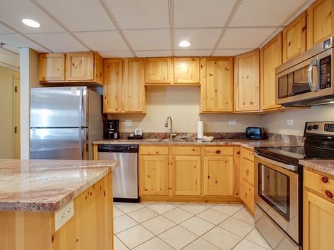Your fully equipped kitchen with warm wood cabinetry, granite counters, stainless appliances, and all the essentials you need to whip up delicious meals together during your stay.