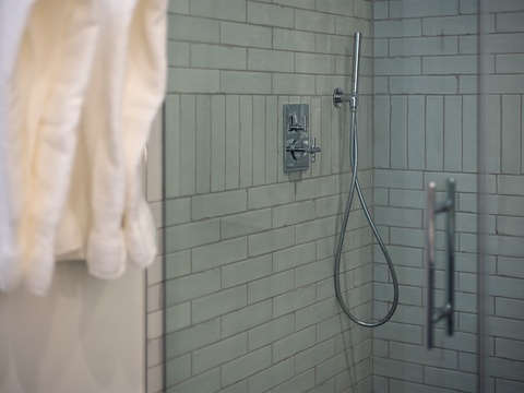 Step into your sleek tiled shower, where fresh towels and modern fixtures await. The handheld showerhead gives you flexibility while the clean glass enclosure keeps everything bright and airy.