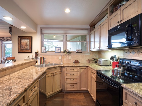 Your fully equipped kitchen features granite countertops, modern appliances, and warm wood cabinetry—perfect for preparing home-cooked meals during your stay.