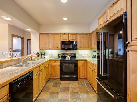 Step into your fully-equipped kitchen, where warm wood cabinetry and modern appliances invite you to whip up home-cooked meals, making every moment deliciously comfortable.