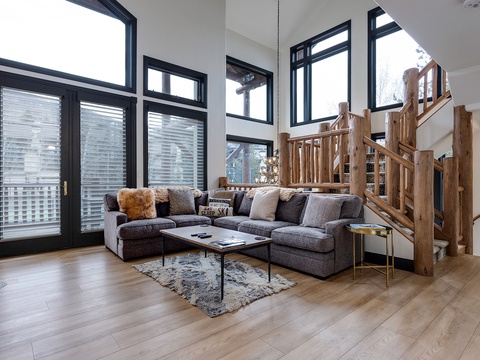 Sink into this plush sectional in your sunlit living room, where soaring ceilings and rustic wood details meet modern mountain comfort. Large windows frame treetop views for peaceful mornings and cozy evenings.