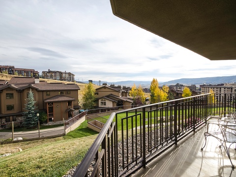 The balcony overlooks a scenic mountain valley framed by autumn foliage and neighboring properties, providing a peaceful setting for relaxation.