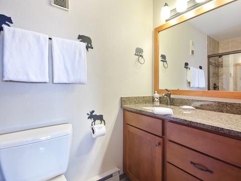 Your private bathroom features granite counters, warm wood cabinetry, and charming woodland touches—soft towels and peaceful lighting make it feel like a mountain retreat.
