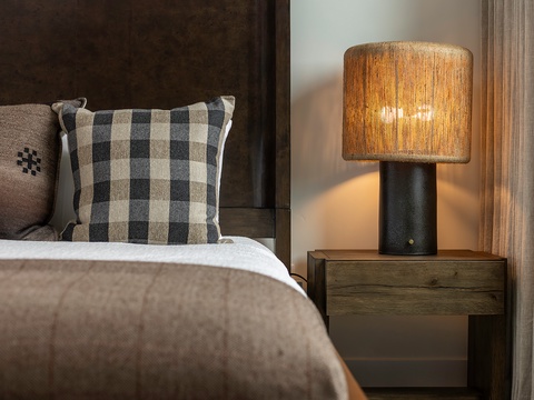 Sink into plush bedding beneath a rustic wood headboard, where warm lighting and stylish textures create your perfect retreat for restful mountain evenings.