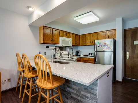 Your fully equipped kitchen features warm wood cabinetry, modern appliances, and a welcoming breakfast bar where you can gather for meals or plan your day's adventures.