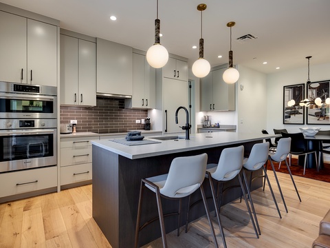 Gather around this sleek chef's kitchen, where modern appliances and stylish pendant lighting create the perfect space for your culinary adventures and morning coffee rituals.