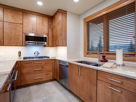 Cook your favorite meals in a beautiful kitchen with modern appliances, warm wood cabinetry, ample counter space, and a window view to inspire your culinary creations.