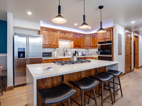 Your gourmet kitchen awaits with gleaming stainless-steel appliances, rich wood cabinetry, and a spacious island perfect for cooking together or enjoying morning coffee.