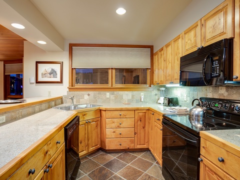 Your fully-equipped kitchen features warm wood cabinetry, modern appliances, and ample counter space—perfect for preparing meals or brewing morning coffee in the comfort of your mountain retreat.