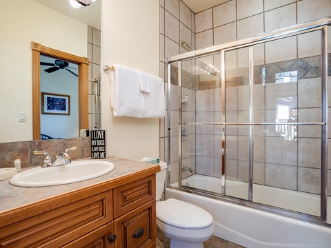 Freshen up in your private bathroom with neutral tile, a glass-enclosed tub-shower combo, and all the essentials waiting for you.