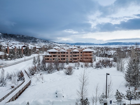 An aerial perspective of the mountain resort in winter reveals the property nestled among snow-covered slopes, evergreens, and distant peaks—capturing the alpine setting and seasonal landscape surrounding the accommodations.
