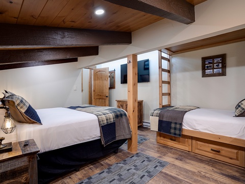 Picture yourself unwinding in this rustic yet modern bedroom. Warm wooden accents and exposed beams create a cozy mountain retreat vibe, while plaid throws and multiple sleeping arrangements promise comfort for your group.