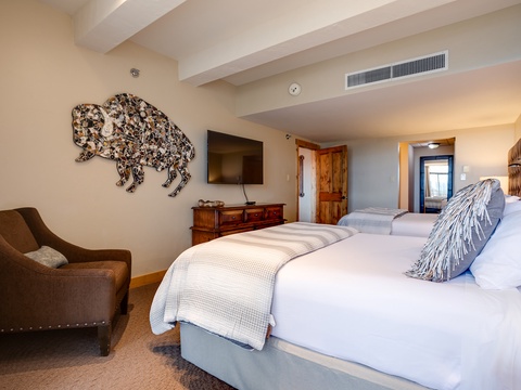 Sink into plush bedding and unwind in your spacious bedroom, featuring two inviting beds, a cozy sitting area, and mountain-inspired décor that makes you feel right at home.