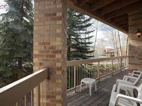 Your private covered deck overlooks towering evergreens and peaceful wooded surroundings—perfect for morning coffee or quiet evenings under the exposed beam ceiling.