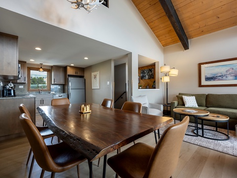 Gather around a stunning live-edge dining table where your group can share meals and stories, then unwind in the cozy lounge area—all beneath soaring vaulted ceilings with warm wood beams.