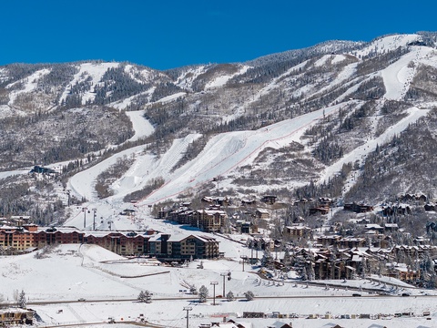 A winter resort nestled in pristine snow-covered mountains, featuring groomed ski runs and charming alpine lodges throughout the valley.