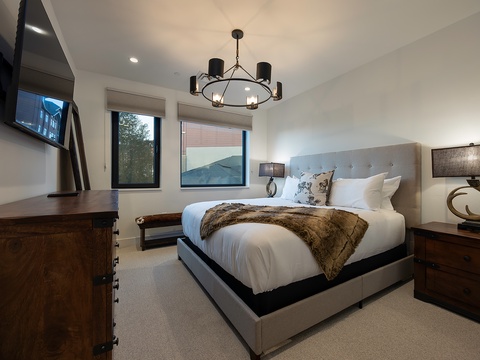 Sink into crisp linens and a plush faux-fur throw in your beautifully appointed bedroom, where natural light pours through dual windows and warm wood accents create a cozy retreat.