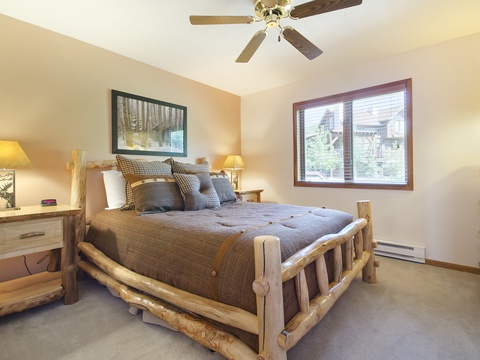 Sink into this cozy bedroom with rustic log-frame bed, soft lighting, and a ceiling fan to keep you comfortable. Your forest-framed window offers peaceful natural views as you unwind.
