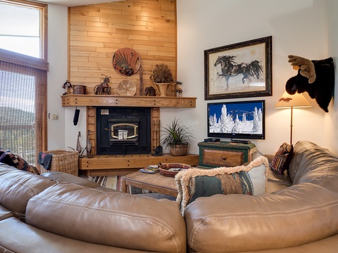 Sink into plush leather sofas by the crackling wood-burning fireplace, where rustic western charm meets cozy mountain comfort in your inviting living room retreat.