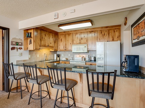 Your fully equipped kitchen with warm wood cabinetry and granite countertops invites you to whip up meals or enjoy morning coffee at the breakfast bar seating four.