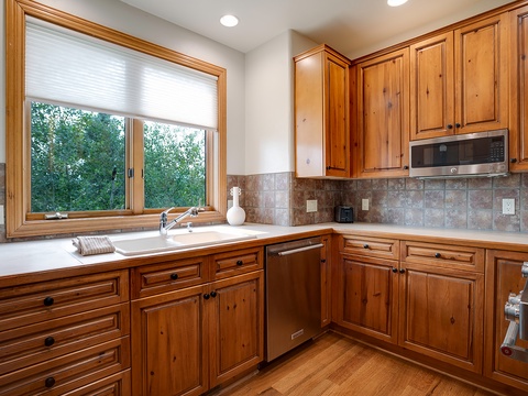 Prepare your favorite meals in this fully equipped kitchen with warm wood cabinetry, modern appliances, and a window that invites natural light over the sink.