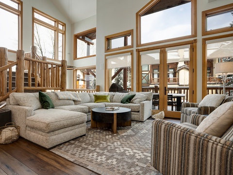 Sink into plush sofas in this stunning mountain retreat, where soaring windows frame snowy forest views and rustic log accents create your perfect alpine escape.