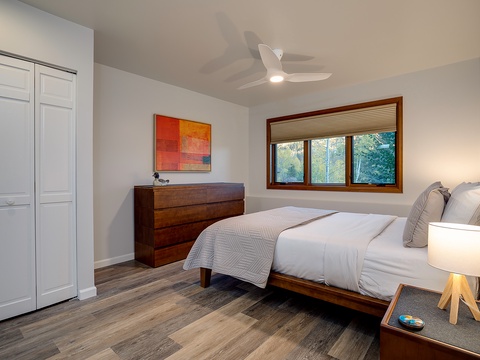 Sink into crisp linens and feel the ceiling fan's gentle breeze as natural light and leafy views invite you to unwind in your serene retreat.