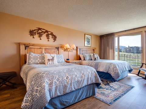 Unwind in this inviting bedroom with two plush queen beds, mountain-themed décor, and your own private balcony overlooking sweeping mountain and valley views.