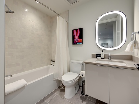 Unwind in your pristine bathroom, featuring a luxurious soaking tub, walk-in shower, and modern fixtures bathed in soft ambient lighting.