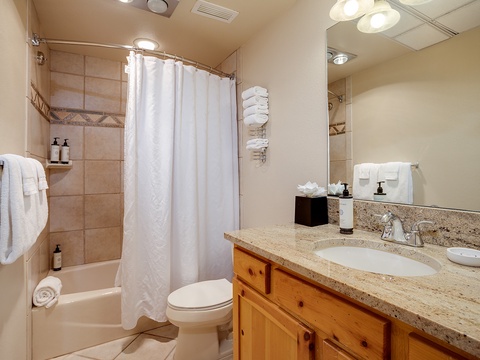 Your private bathroom features a spacious granite vanity, plush towels, a refreshing shower-tub combo, and warm pine cabinetry—everything you need to unwind after a day of adventure.