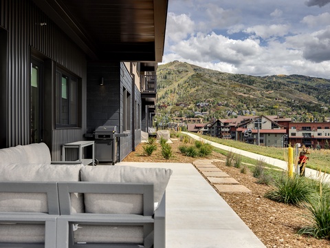 Dramatic mountain views frame your private outdoor living space, complete with BBQ grill and comfortable seating. Watch as clouds drift over the peaks while you unwind on the patio.