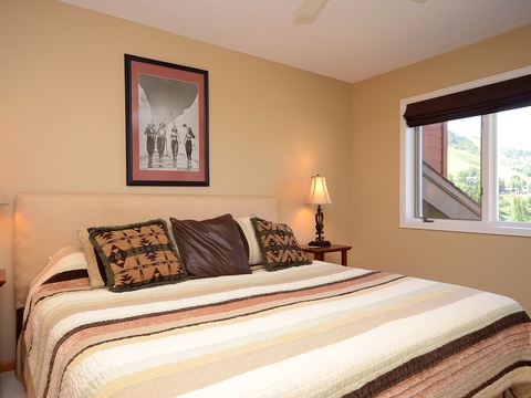 Drift off in this cozy bedroom with warm tones, stylish art, and a window framing beautiful mountain views—your perfect retreat after a day of adventure.