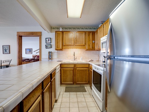 Your fully equipped kitchen awaits with plenty of counter space, warm wood cabinetry, and modern appliances—perfect for cooking up memorable vacation meals together.