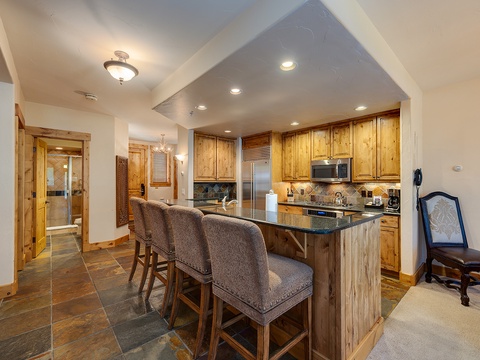 Gather around your fully equipped kitchen island with bar seating, featuring warm wood cabinetry, granite countertops, and stainless steel appliances—everything you need for easy vacation meals.