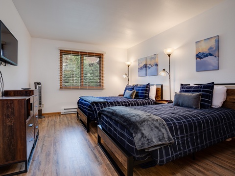 Your peaceful retreat features two plush beds with soft linens, mountain art, warm lighting, and a flat-screen TV—perfect for unwinding after a day of adventure.
