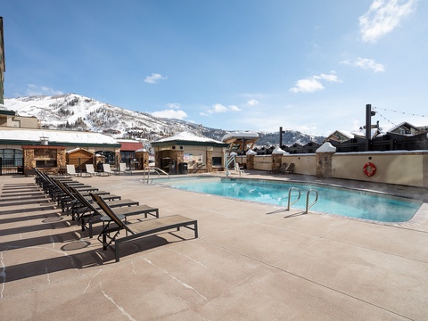 An outdoor heated pool with stunning mountain backdrop offers year-round relaxation. Lounge chairs line the deck, perfect for soaking up alpine sunshine after a day on the slopes.