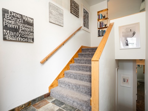 Bright stairway with warm timber rails and custom built-in shelving, connecting your living spaces. Local beach artwork adds coastal character to this welcoming home.